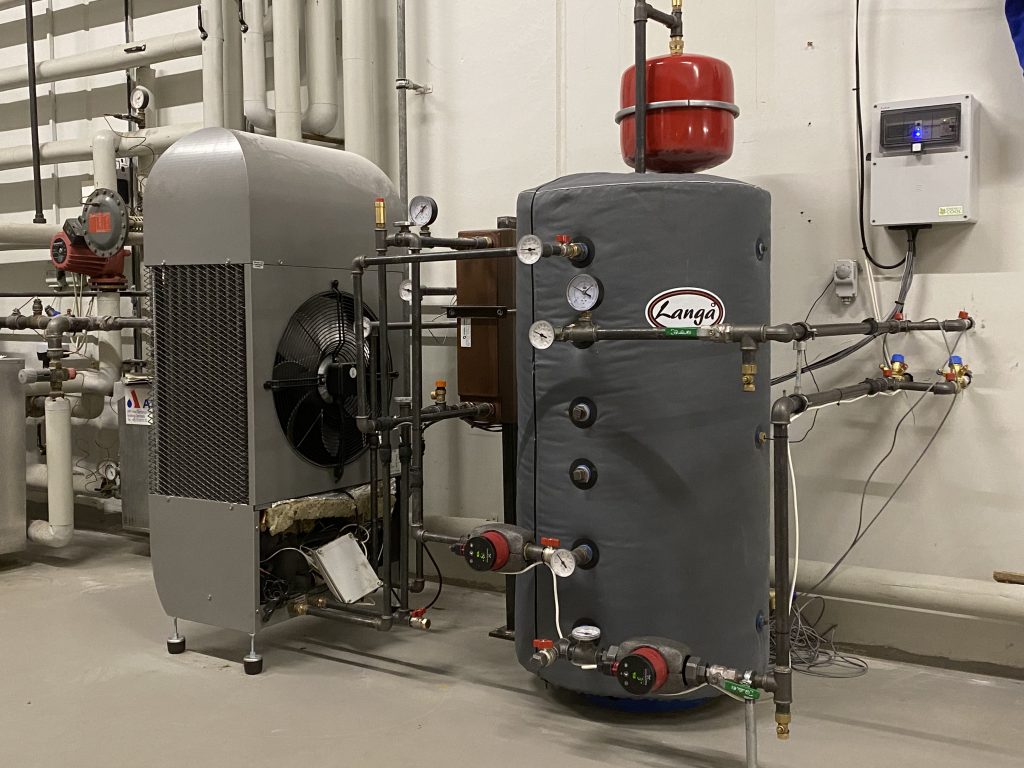 The  absorption chiller is the grey instrument at left.  The pilot chiller is a small unit of 2.5 kW. It cools the district heating water from 60 degrees to 13-18 degrees and passes it through a valve into a fan coil to cool the air.  Credit: GEV